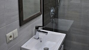 A modern bathroom with a large mirror, a white sink, and a glass shower enclosure.