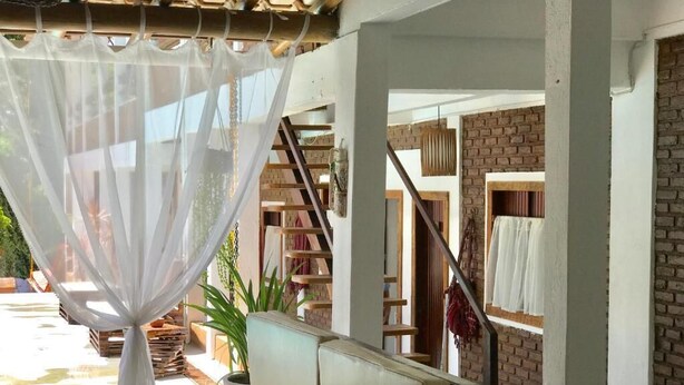 A cozy indoor space with a cushioned seating area, a staircase, and a view of the outdoors. - Pousada Arraial da Poesia (Porto Seguro)
