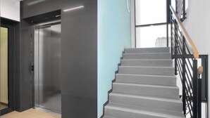 A modern interior with a staircase, a door, and a light blue wall. - Elite Apartments Mila (Gdansk)