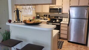 Una cocina moderna con una isla central, electrodomésticos de acero inoxidable y armarios de madera clara.