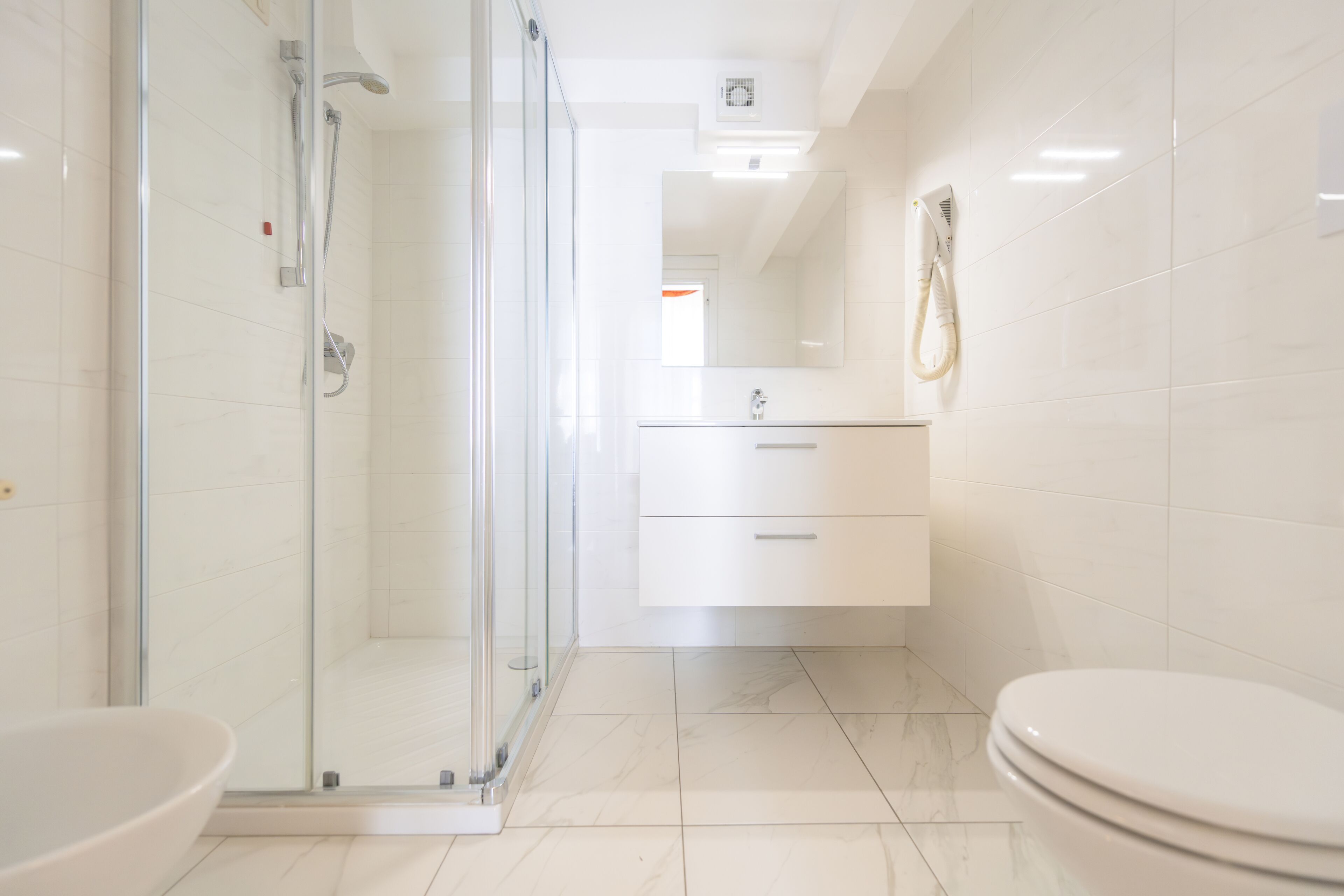 A modern bathroom with a glass-enclosed shower, a white sink, and a toilet.