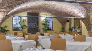 A restaurant with multiple tables set for dining, featuring a rustic brick ceiling and large windows.