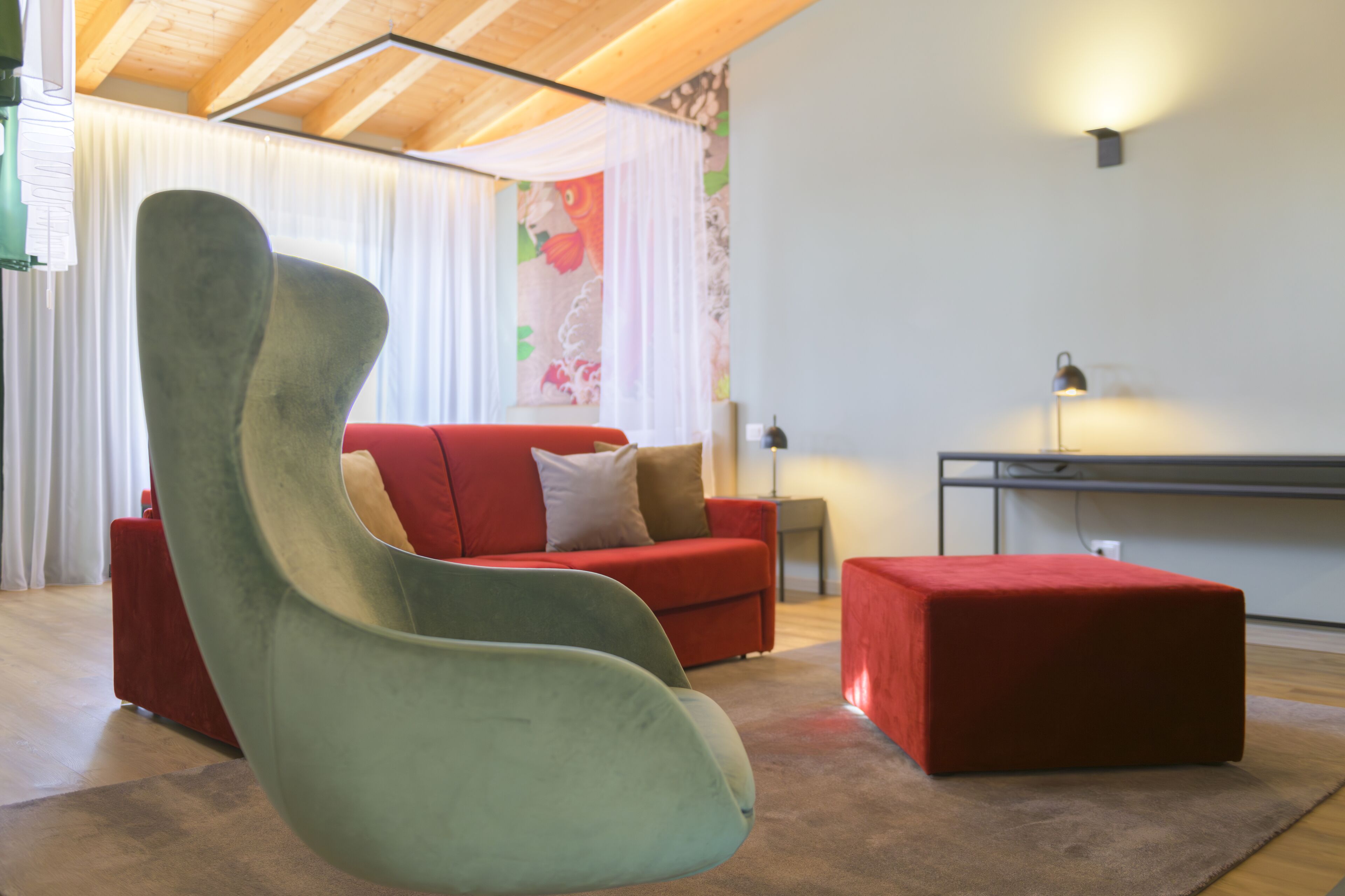 A modern living room with a red sofa, a green chair, and a red ottoman.