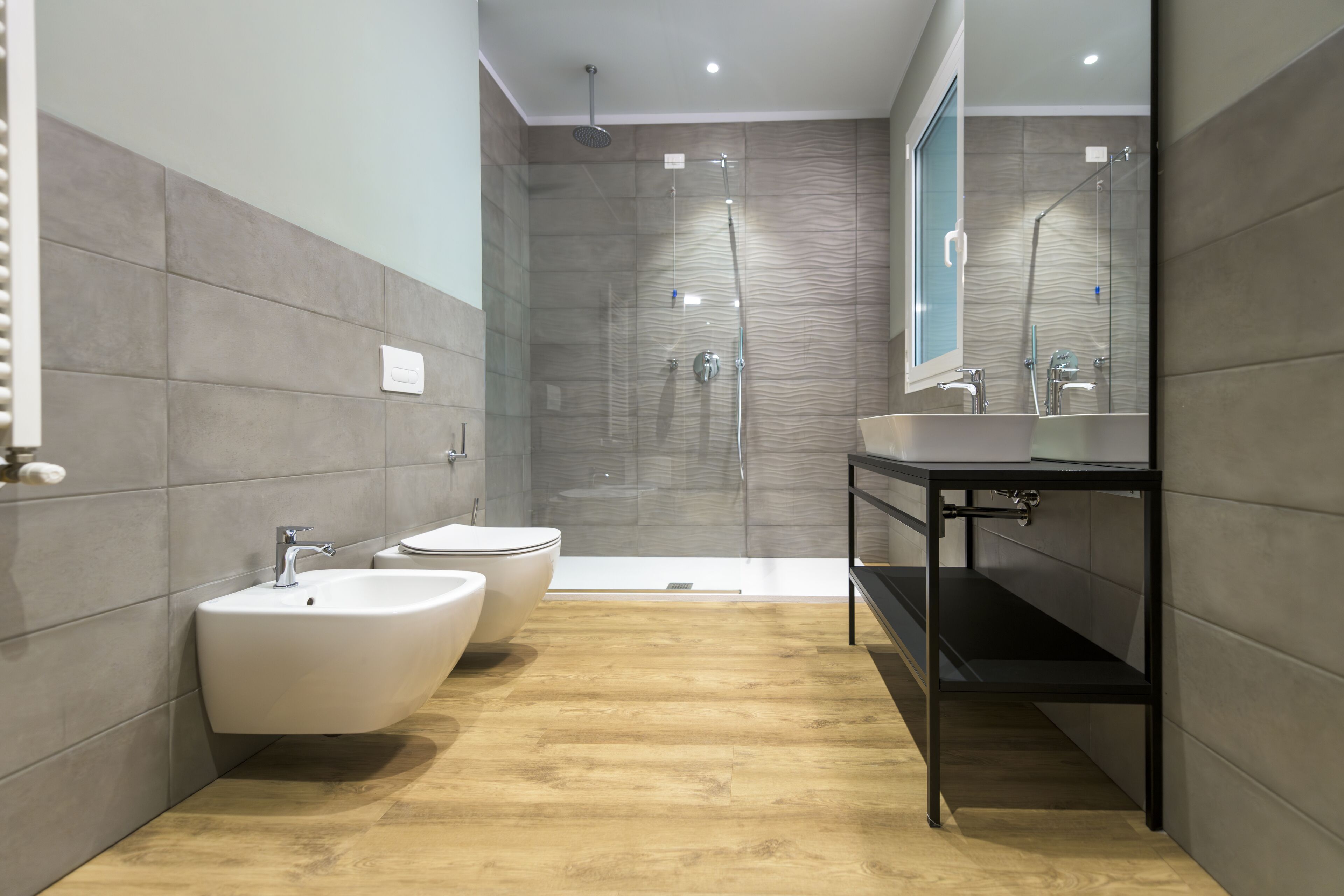 Un baño moderno con dos lavamanos, ducha y espejo.