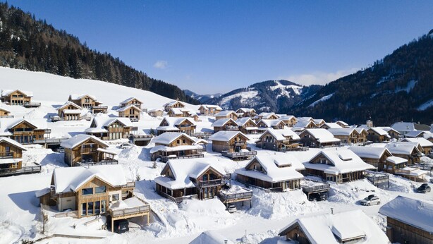 Ein schneebedecktes Resort mit Holzhütten und einer Bergkulisse.