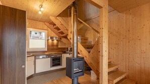 Ein Holzinnenraum mit einer Küche, einem eingebauten Holzofen und einer Treppe.