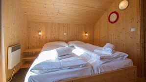 Ein Holzhütten-Zimmer mit zwei Betten, einem Heizkörper und Wandleuchten.