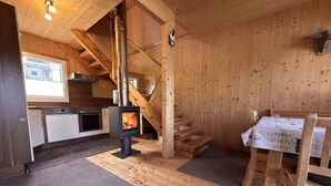 Ein Holzinnenraum mit Küche, Kamin und Essbereich.