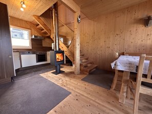 Ein Holzinnenraum mit Küche, Kamin und Essbereich.