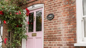 Une porte rose portant le numéro 36, un mur de briques et une enseigne sur laquelle on peut lire « Villa Rosa ».