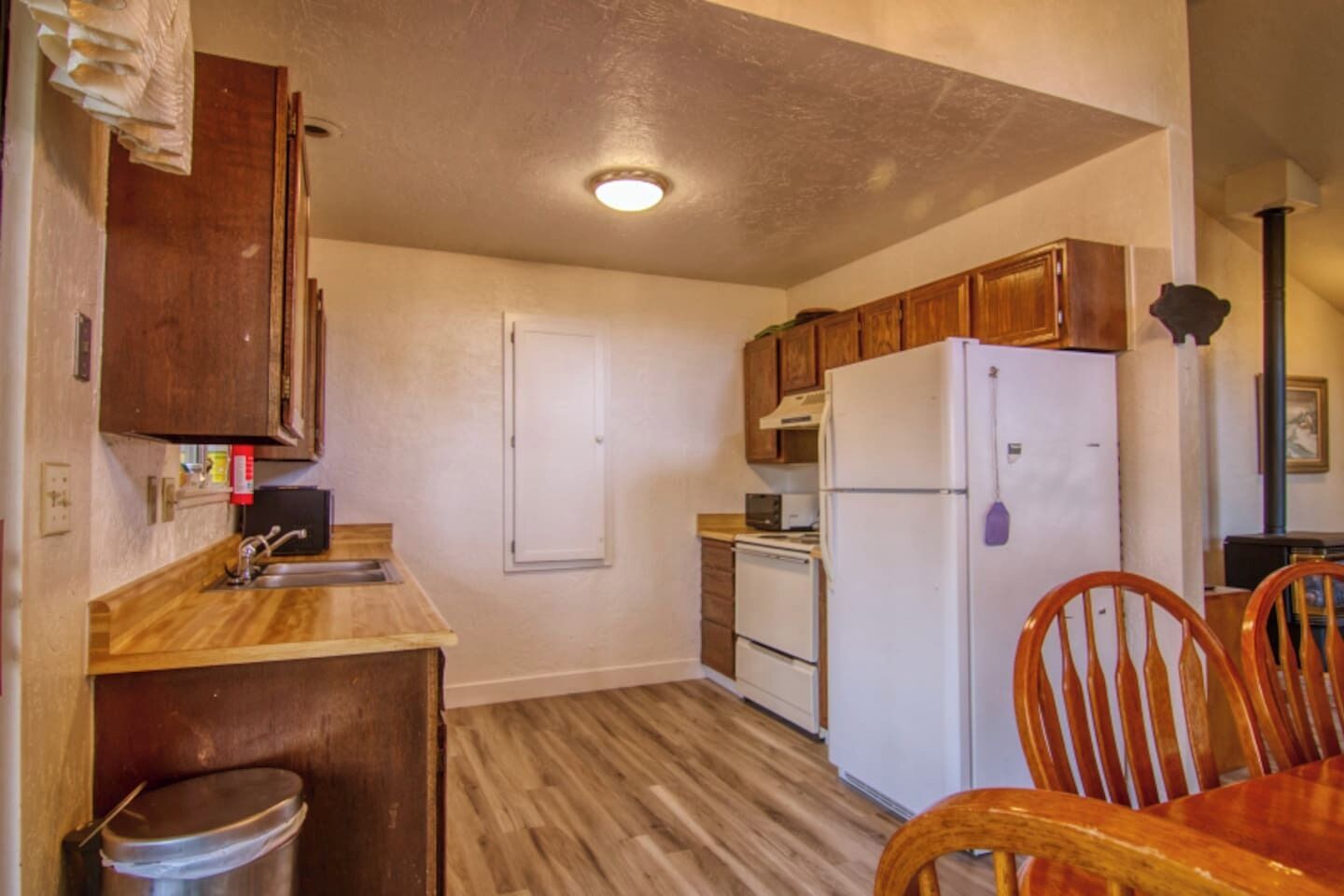 A compact kitchen with wooden cabinets, a white refrigerator, a microwave, and a sink.
