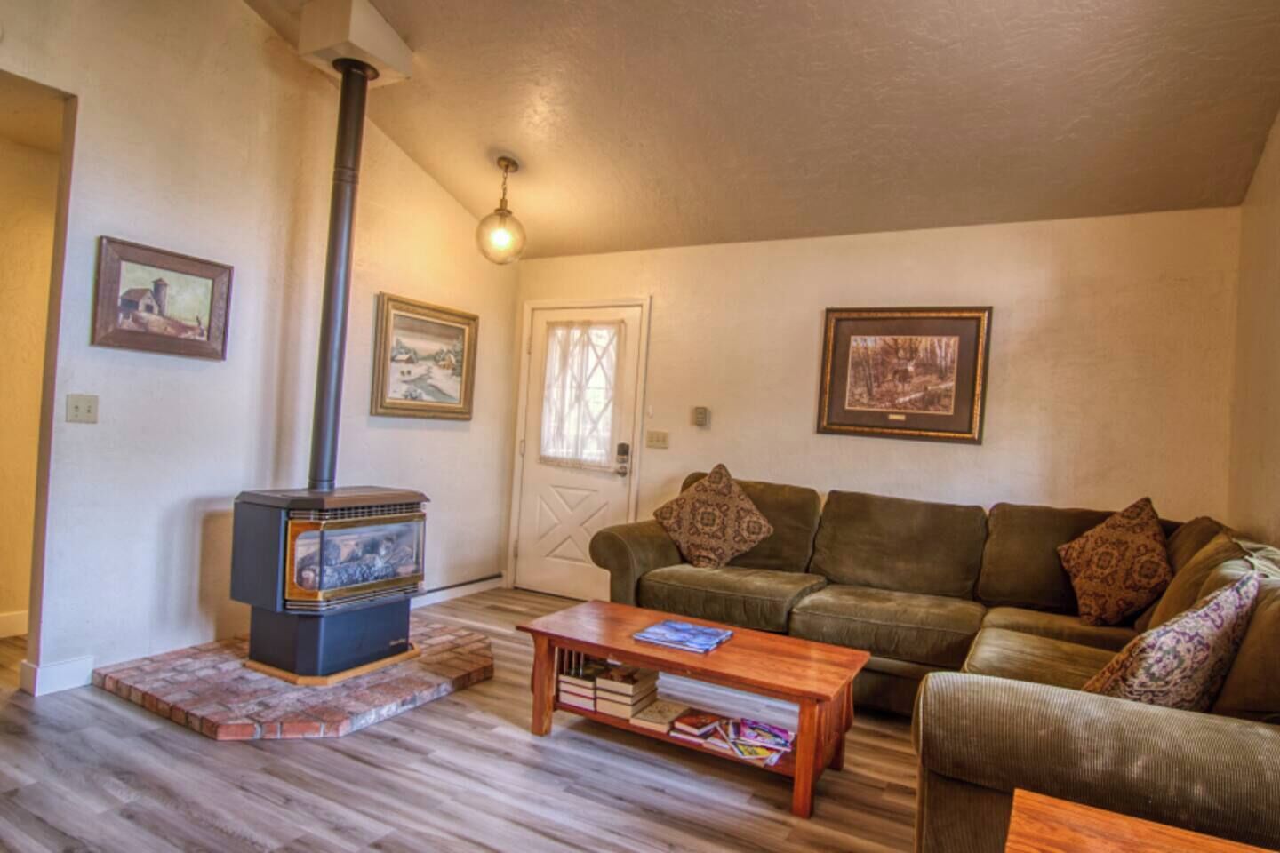 A cozy living room with a wood-burning stove, a brown leather sofa, and a wooden coffee table.