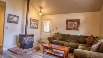 A cozy living room with a wood-burning stove, a brown leather sofa, and a wooden coffee table.