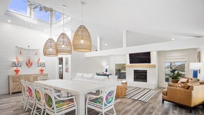 A spacious living area with a white dining table, colorful chairs, a fireplace, and a large TV. - Private Pool | LSV | 2 Min Walk to Beach (Santa Rosa Beach)