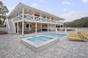 A two-story house with a covered patio area, a swimming pool, and outdoor seating.