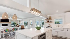 A modern kitchen with white cabinetry, a large island, and a dining area with colorful chairs. - Private Pool | LSV | 2 Min Walk to Beach (Santa Rosa Beach)