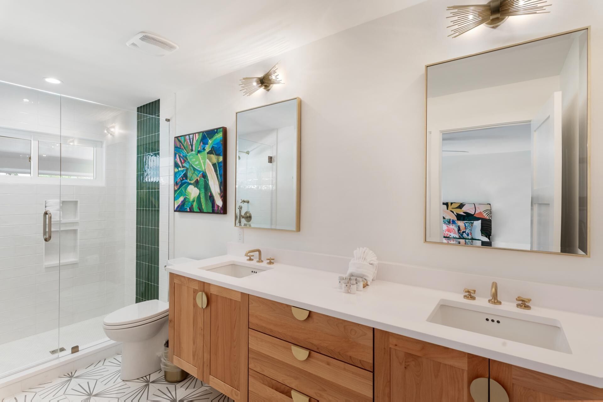 Een moderne badkamer met een douchecabine van glas, een wit wastafelmeubel met gouden details en een grote spiegel erboven.