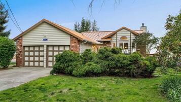 A two-story house with a garage, a brick chimney, and a well-maintained lawn.
