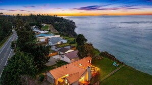 Un quartier résidentiel situé sur la côte, avec des maisons, une route et une vue sur la mer au coucher du soleil.