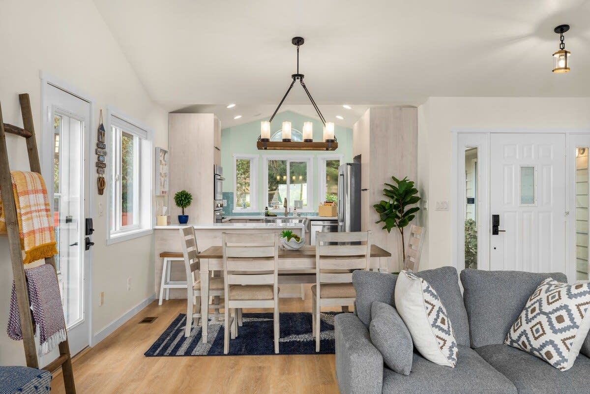 A modern kitchen with a central island, white cabinetry, and a hanging light fixture.
