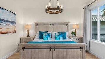 A bedroom with a wooden bed, two bedside tables, a chandelier, and a large window with curtains.
