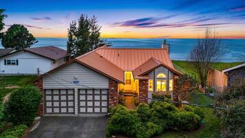 A house with a garage, a driveway, and a view of the ocean at sunset.