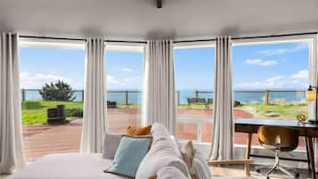Un dormitorio con una cama grande, un escritorio y vista al mar.