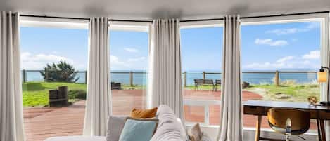 A bedroom with a large bed, a desk, and a view of the sea.