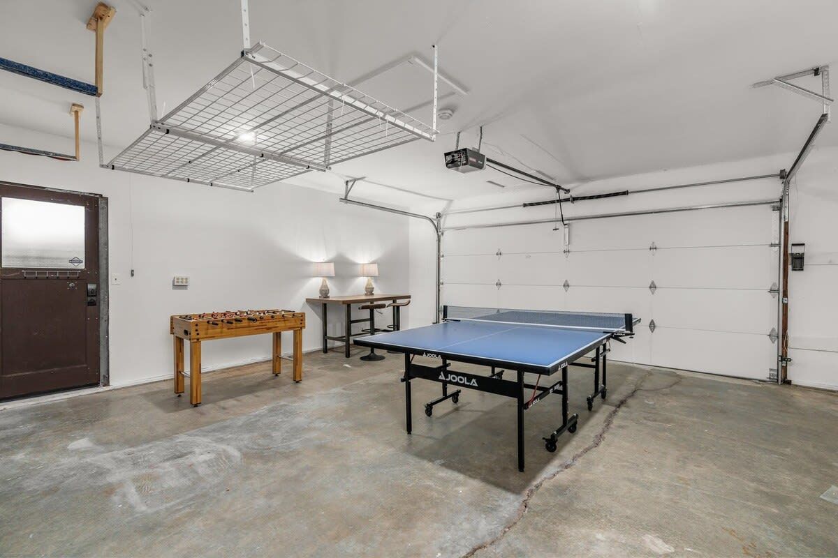 Una habitación amplia con mesa de ping pong, mesa de futbolín y proyector montado en el techo.