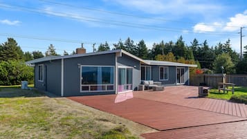 Una casa moderna con una terraza grande, un porche cubierto y un garaje.