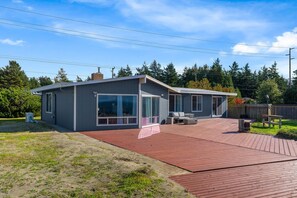 Une maison moderne dotée d’une grande terrasse, d’un patio couvert et d’un garage.