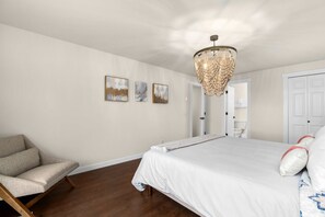 Un dormitorio con una cama grande, una silla y una araña.
