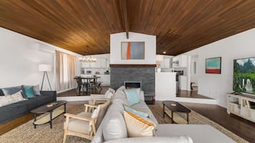 Una sala de estar moderna con chimenea, comedor y cocina.