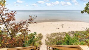 Une promenade en bois mène à une plage de sable, d’où l’on a une vue sur l’océan.