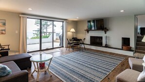Un salon moderne doté d’une cheminée, d’un coin repas et d’une grande porte-fenêtre coulissante donnant sur un balcon.