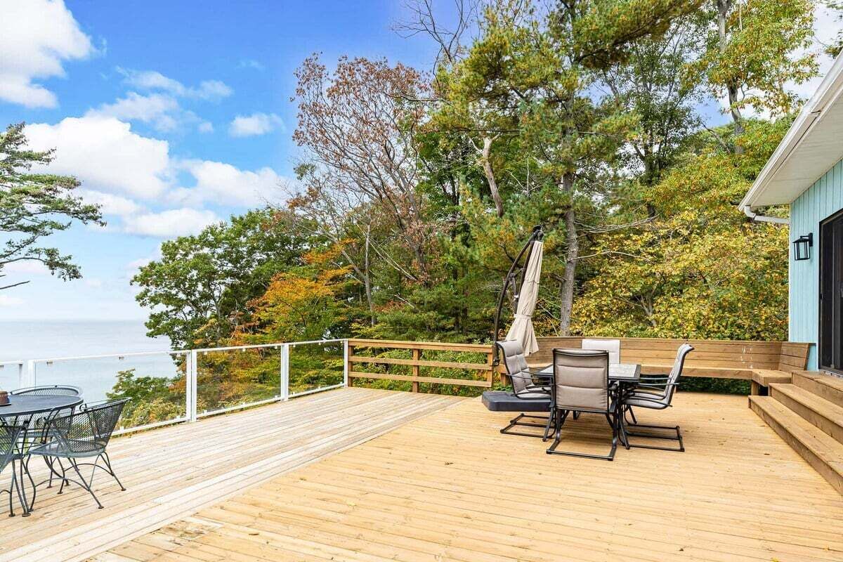 Une terrasse en bois avec des meubles d’extérieur, une balançoire et une vue sur l’océan.
