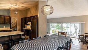 Une cuisine moderne avec des meubles en bois foncé, un îlot central et un coin repas agrémenté d’une nappe à carreaux.