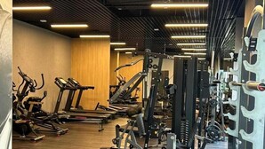 Uma academia com esteiras, máquinas de musculação e pesos livres.