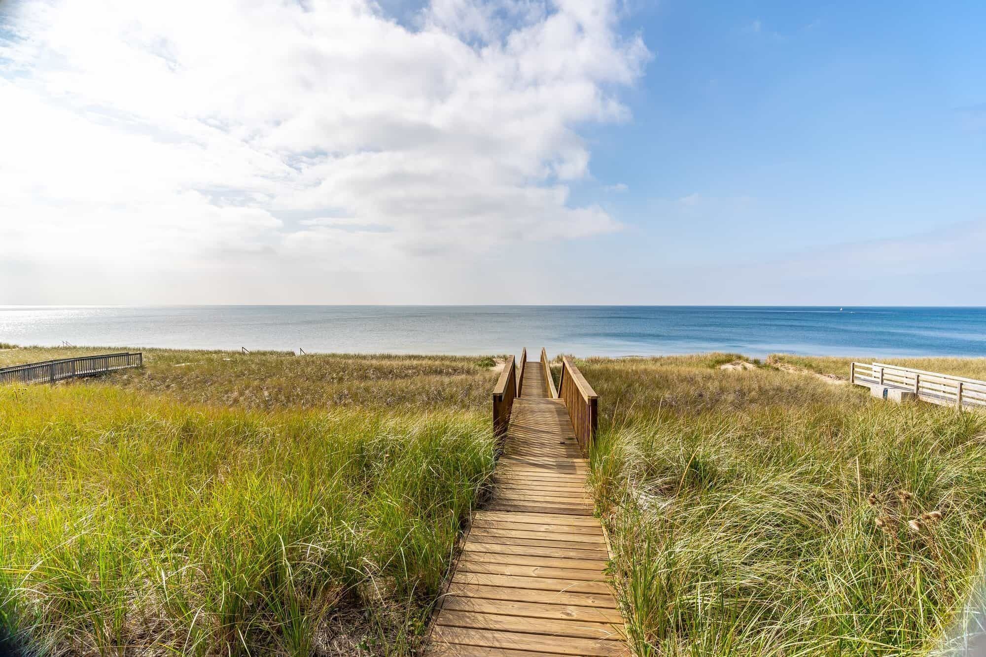 A wooden boardwalk leading to a beach with a clear view of the ocean.