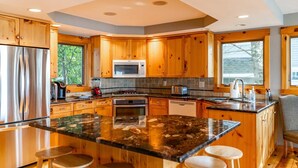 Une cuisine moderne avec des meubles en bois, un plan de travail en granit et un îlot central doté de tabourets de bar.