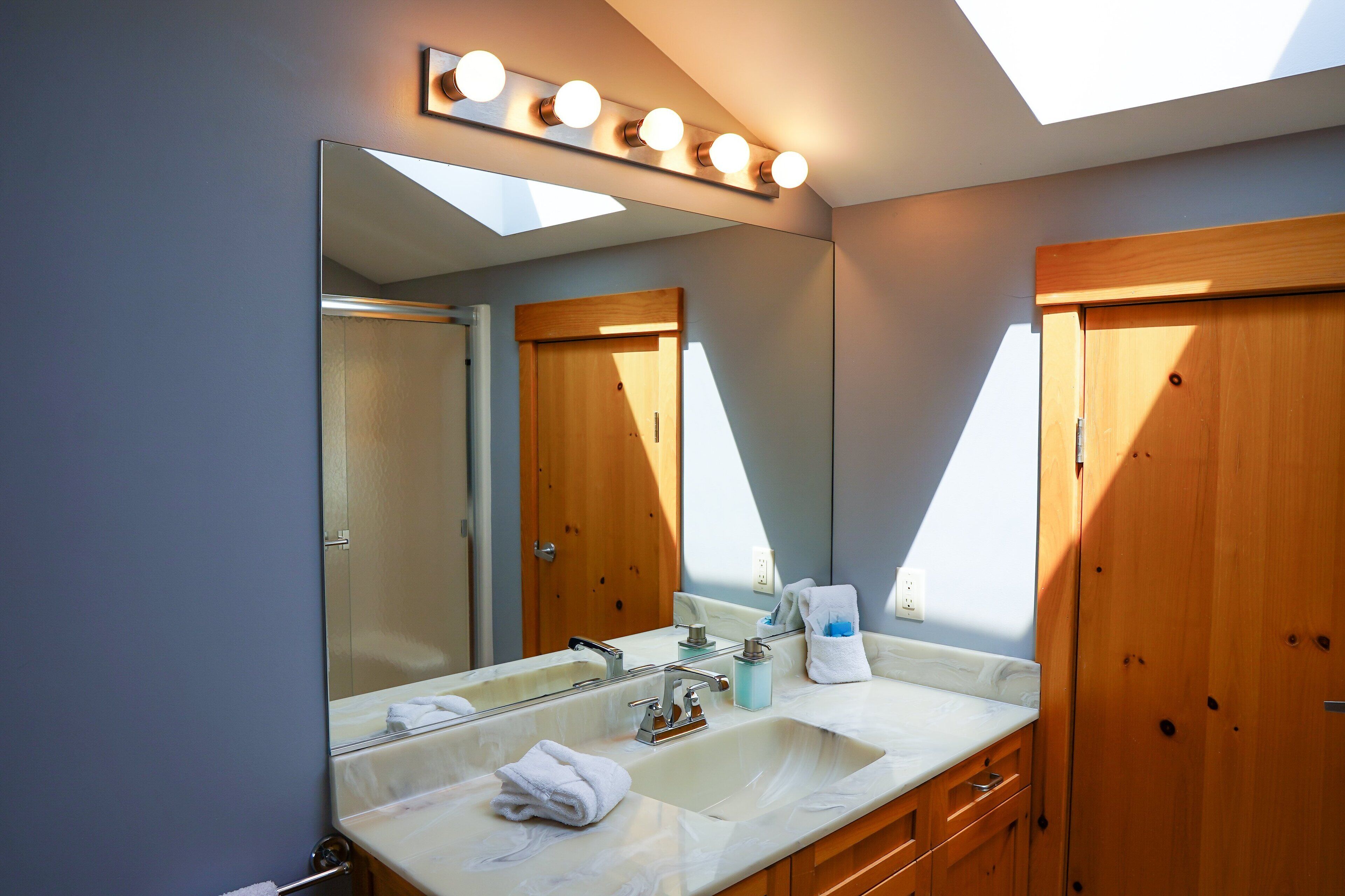 A bathroom with a large mirror, vanity, and wooden cabinets.