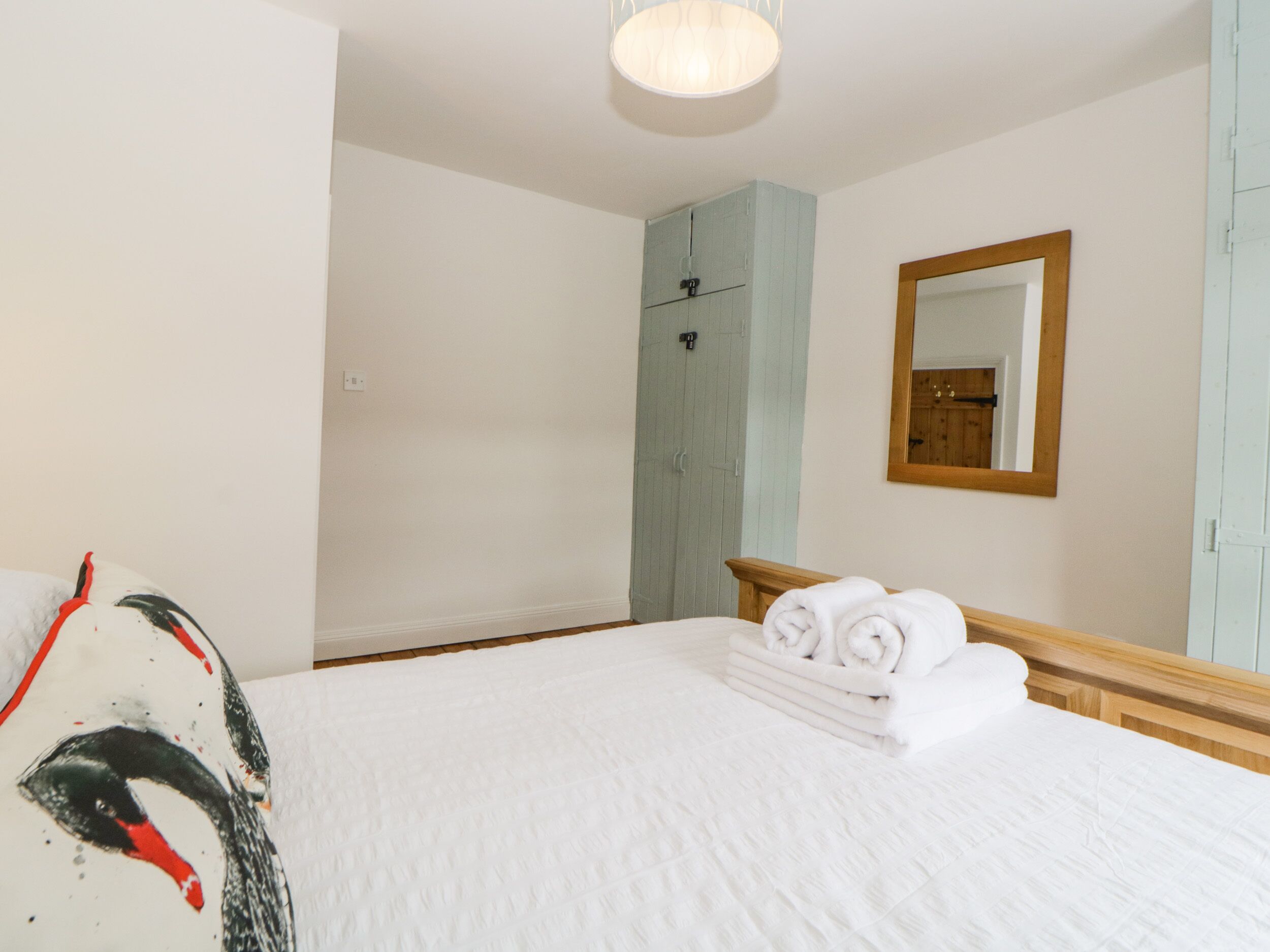 A hotel room with a bed, a wooden headboard, a mirror, and a wardrobe.