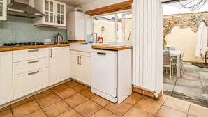 A kitchen with white cabinets, a gas stove, and a built-in dishwasher. - The Yellow House, 13 King Street (Dawlish)