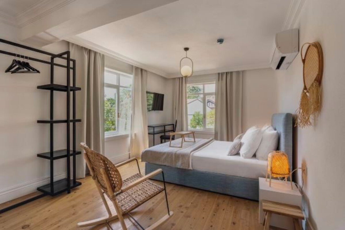 A modern bedroom with a bed, a chair, a desk, and a TV.