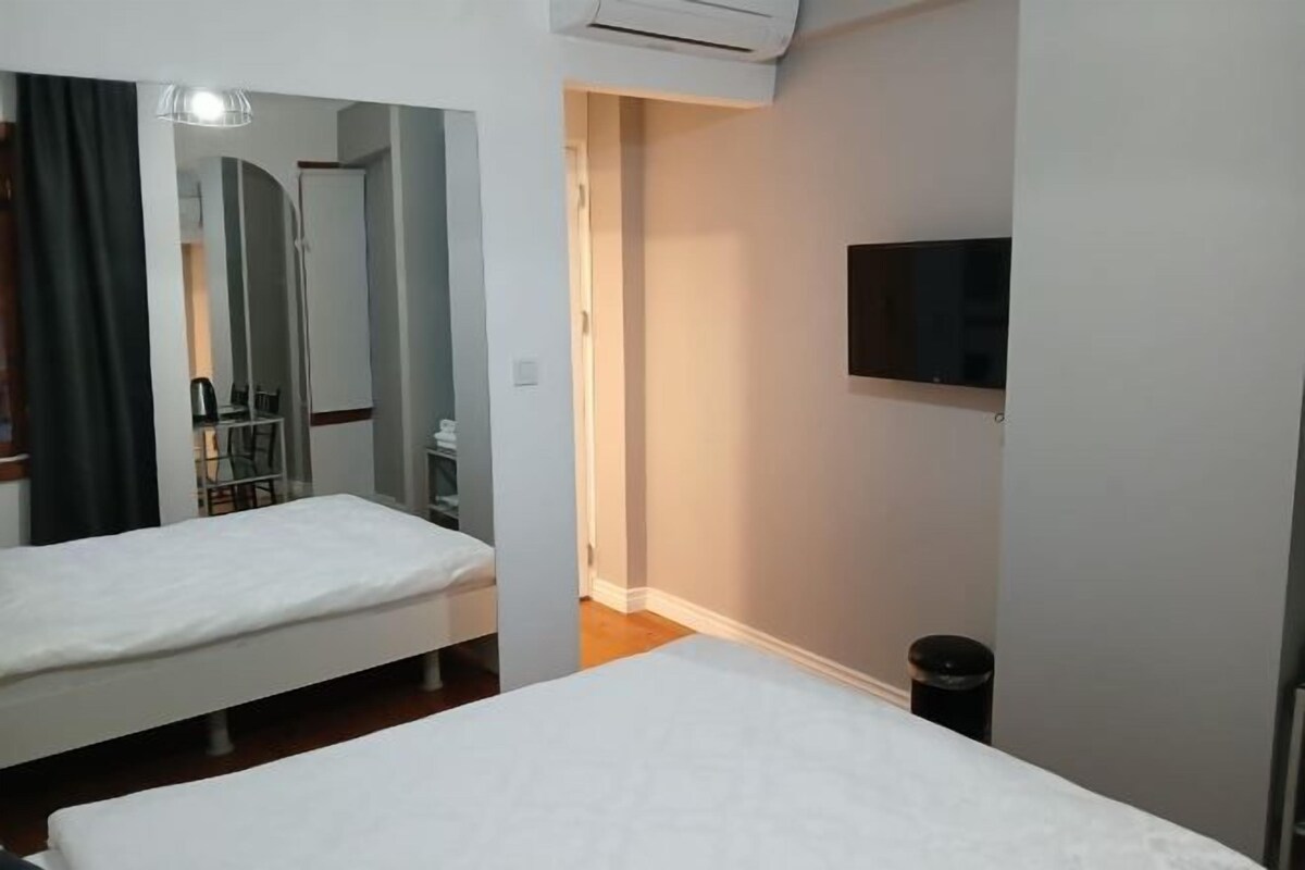 A hotel room with two beds, a TV mounted on the wall, and a small trash bin.