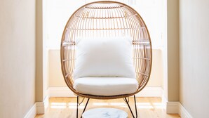 A room with a large window, a white chair, and a hanging light fixture. - House of Good Things (Antalya)