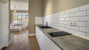 A modern kitchen with white subway tiles, a black induction cooktop, and a built-in sink. - House of Good Things (Antalya)