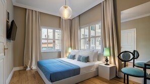 A bedroom with a large bed, two bedside tables, a chair, a TV, and a window with curtains. - House of Good Things (Antalya)