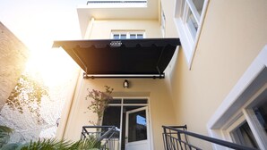 A building entrance with a black awning, a white door, and a small outdoor area with plants. - House of Good Things (Antalya)