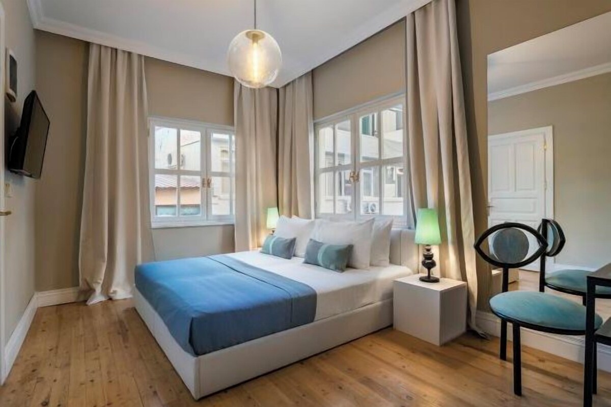 Un dormitorio con cama, mesitas de noche, lámpara y una silla.